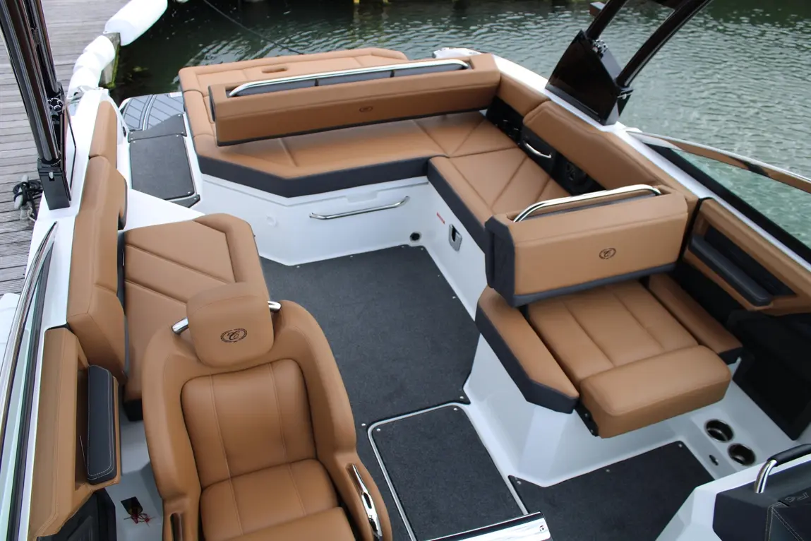 Spacious boat interior featuring plush brown seating, sleek design, and a scenic water view, ideal for relaxation and leisure.